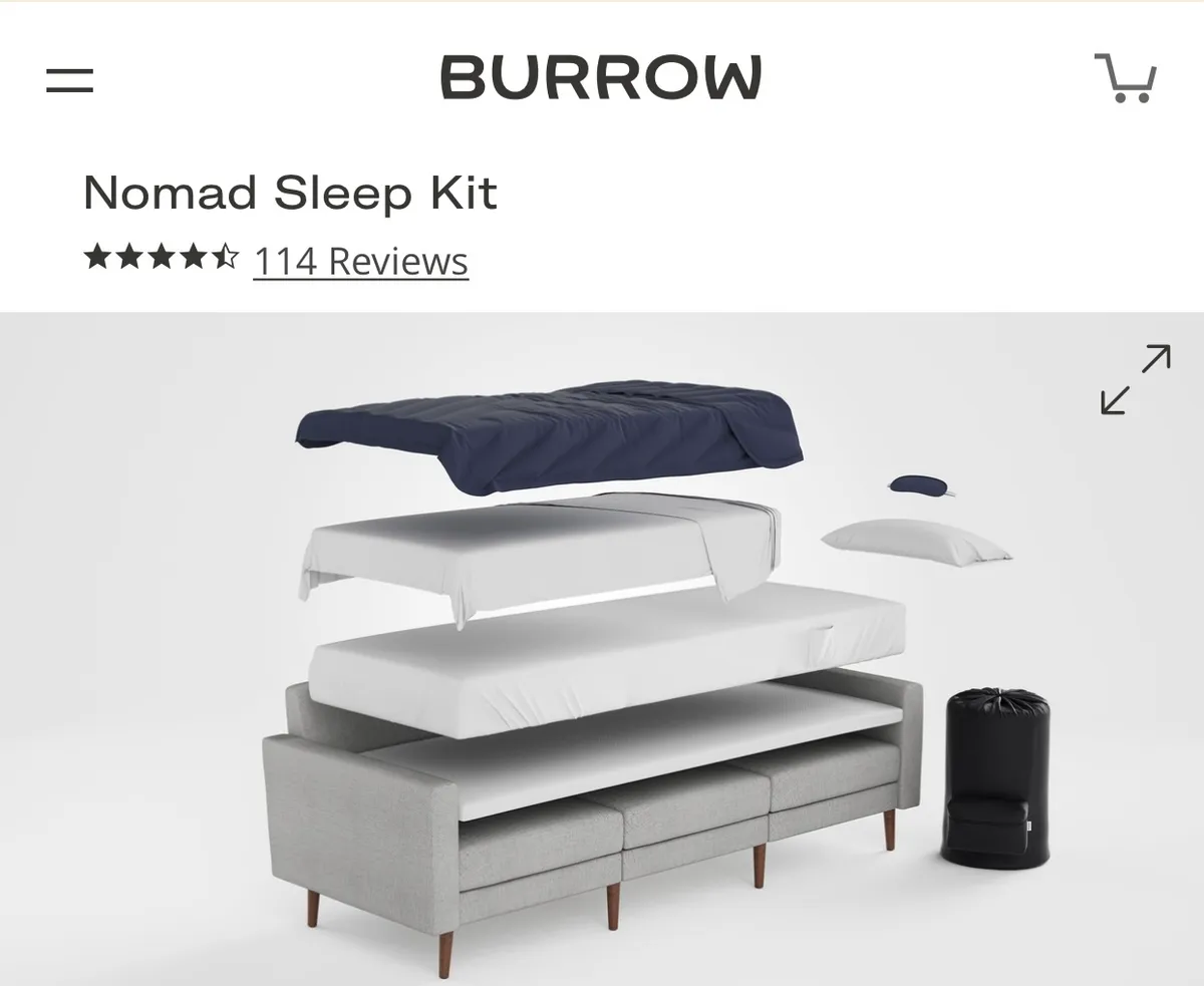 The scene features a gray couch set up with mattress layers, a sleeping bag, and pillow, illustrating how the living room transforms into an additional sleeping nook. The setup is casual, practical, and inviting, highlighting flexibility for extra guests or children seeking their own comfortable corner.