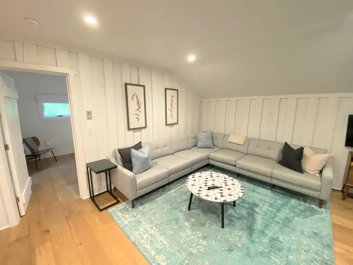 A cozy interior living area featuring a sectional sofa, coffee table, and tasteful artwork. The setting is casual yet inviting, with warm lighting and an ambiance ideal for relaxing after a day of exploring the Highlands. The layout suggests a space for couples to unwind, share stories, or enjoy each other's company in comfort.